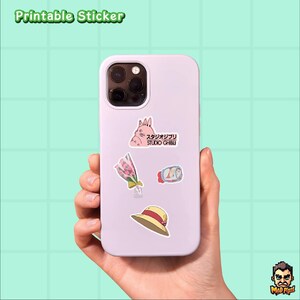 May include: A light purple phone case with several stickers applied. The stickers include a pink cartoon rabbit, a bouquet of flowers, a roll of food, and a straw hat. The text "Printable Sticker" is at the top.