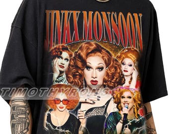 Puede incluir: Una camiseta negra de manga corta con un estampado gráfico de Jinkx Monsoon en varias poses y atuendos. El texto JINKX MONSOON está impreso en letras grandes de color naranja y rojo en la parte superior. El diseño incluye efectos de rayos y marca de agua.