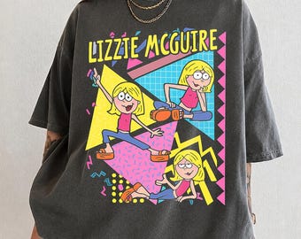 Puede incluir: Una camiseta de manga corta gris carbón con un estampado gráfico del personaje Lizzie McGuire en tres poses diferentes. El diseño incluye formas geométricas, patrones y el texto LIZZIE MCGUIRE en colores amarillo, rosa y azul brillantes.