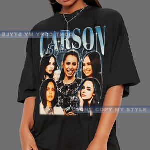 May include: Black t-shirt featuring a graphic of Sofia Carson with the text "CARSON Sofia" in a vintage style. The design includes multiple images of Sofia Carson. The shirt is a casual wear item.