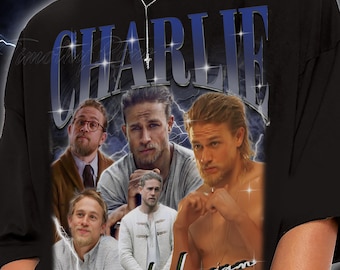 Puede incluir: Camiseta negra con un gráfico de varios hombres y el nombre "CHARLIE" en azul. El diseño tiene un aspecto vintage con efectos de rayos. La camiseta la lleva una persona.