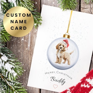 May include: A Christmas card with a watercolour illustration of a puppy in a Santa hat inside a snow globe ornament. The card reads "Merry Christmas Buddy" with a heart. A gold circle with "CUSTOM NAME CARD" is also visible.