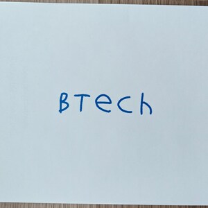 May include: A white sheet of paper with the word "BTech" written in blue ink. The text is centered on the page.