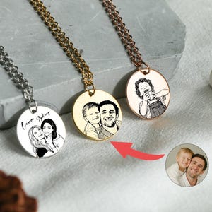 May include: Three personalized necklaces with engraved portraits. One is silver, one gold, and one rose gold. Each pendant is a circular disc with a chain. The pendants feature custom portraits of people.