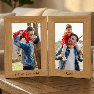 Könnte beinhalten: Ein zweiteiliger, hellbrauner Holzfotorahmen. Jede Seite zeigt ein Foto einer Person mit einem Kind. Der linke Rahmen trägt die Aufschrift "I love you Dad", der rechte Rahmen "Rita".