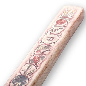 以下が含まれることがあります： ザクロ、レモン、ブドウ、イチジク、ナツメヤシ、小麦の穂を特徴とする装飾的なデザインが施された白いセラミックのメズーザ。メズーザは、家のドアの枠に取り付けられる伝統的なユダヤ教の宗教的な物体です。