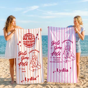 Puede incluir: Dos toallas de playa a rayas verticales con texto. Una es melocotón y blanca, la otra rosa y blanca. Las toallas dicen "Sophia's Bachelorette" y "Girls Gone Mild" con el nombre "Lydia" en cada una. Las toallas se sostienen en una playa.