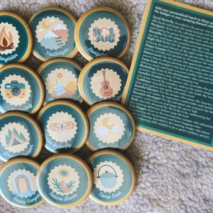 12 pinback buttons with a camping merit badge theme
