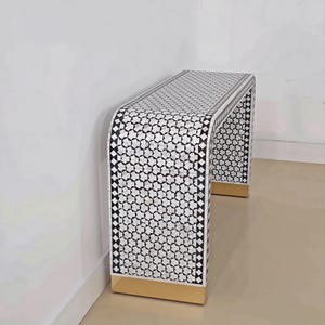 Peut inclure: Une console en cascade avec une incrustation géométrique en forme d'étoile noire et blanche sur le dessus et les côtés. Le meuble est encadré par une bordure en losanges noirs et blancs et repose sur une base en métal doré à chaque extrémité.