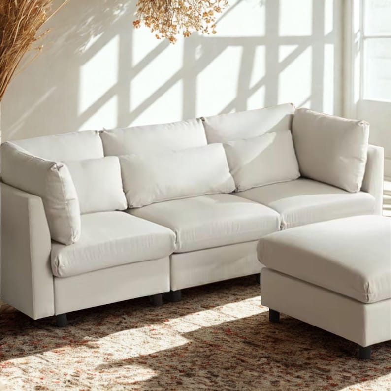 May include: A white sectional sofa with matching ottoman. The sofa has multiple cushions and a low profile. The ottoman is rectangular and sits at the end of the sofa. The furniture is on a patterned rug.