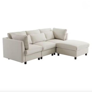 May include: A sectional sofa in a neutral cream color. The sofa has a chaise lounge on the right side and several back cushions. The sofa sits on short, black legs. The overall design is modern and minimalist.