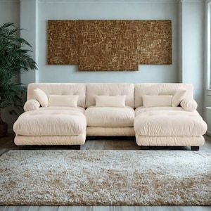 Könnte beinhalten: Ein cremefarbenes Ecksofa mit einer Chaiselongue an jedem Ende. Das Sofa hat mehrere rechteckige und zylindrische Wurfkissen. Über dem Sofa befindet sich ein großer, strukturierter, brauner Wandbehang. Auf dem Boden liegt ein beiger Teppich.