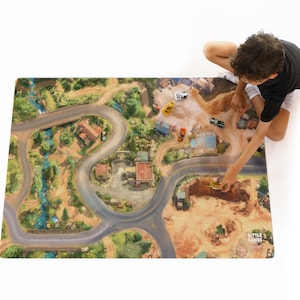 May include: A rectangular play mat featuring a printed aerial view of a landscape with winding roads, a blue stream, green trees, and buildings. The mat includes small toy construction vehicles and the text Little Lands in the bottom corner.