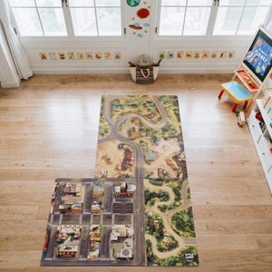 May include: A rectangular play mat featuring a printed design of a city street grid, winding roads, and natural landscapes. The mat is laid out on a light-coloured wooden floor in a room with a white storage unit, a wooden easel, and toys.