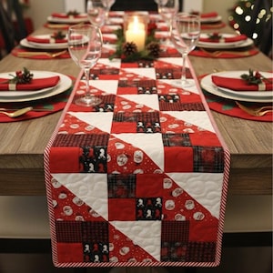 Könnte beinhalten: Ein gesteppter Weihnachtstischläufer mit einem Patchwork-Design in Rot, Weiß und Schwarz. Der Läufer weist eine Vielzahl von Mustern auf, darunter Weihnachtsmann-Gesichter und Karomuster. Der Tisch ist mit Tellern, Gläsern und einer brennenden Kerze gedeckt.