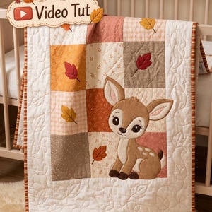 Op de afbeelding: Een patchwork babydeken met een centrale applicatie van een bruin reekalfje met grote ogen. De deken bestaat uit vierkanten in tinten oranje, beige en bruin met bladpatronen en een witte rand met gestikte bladontwerpen en de tekst Video Tut.