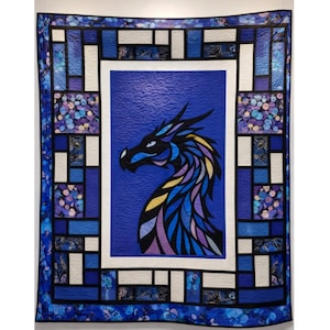 May include: A white ceramic mug with a black handle and the text "But First, Coffee" in a bold, black font. The mug is set against a blurred background, suggesting a cozy setting.