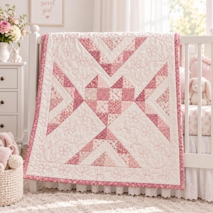 Könnte beinhalten: Eine Babydecke mit einem zentralen Herzmotiv, das aus verschiedenen rosa und weiß gemusterten Blumenstoffquadraten besteht. Die Decke ist mit einer rosa Blumenborte eingefasst und mit gestickten Umrissen von Blumen und Herzen auf weißem Grund verziert.