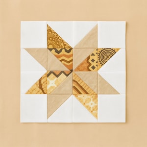 Puede incluir: Un bloque de edredón cuadrado con un diseño de estrella. La estrella está compuesta por triángulos de tela beige, marrón y estampada, sobre un fondo blanco. Los patrones incluyen diseños geométricos y abstractos.