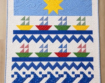 May include: A rectangular quilt featuring a light blue top panel with a yellow star, followed by rows of colourful sailboats in yellow, red, and green. The design includes blue chevron patterns and a bottom border of blue geometric shapes on white.