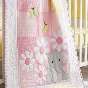 May include: A pink and white baby quilt with a floral and elephant design. The quilt features appliqued daisies, butterflies, and an elephant. The border has a white floral pattern and a pink and white gingham trim. The word "Video" is visible.