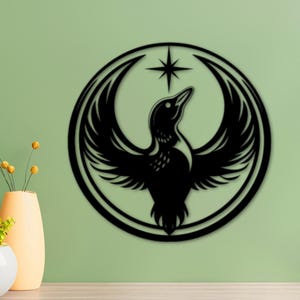 Könnte beinhalten: Schwarze Metall-Wandkunst mit einem stilisierten Vogel mit ausgebreiteten Flügeln in einem kreisförmigen Rahmen. Ein Stern befindet sich über dem Kopf des Vogels. Das Kunstwerk ist an einer hellgrünen Wand angebracht, mit dekorativen Vasen und Pflanzen im Vordergrund.