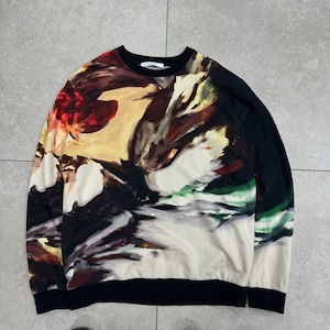 Pode incluir: Camisola de gola redonda com um design floral abstrato em tons de vermelho, amarelo, castanho e verde. A parte superior de manga comprida tem gola e punhos pretos. A parte inferior da camisola também é preta.