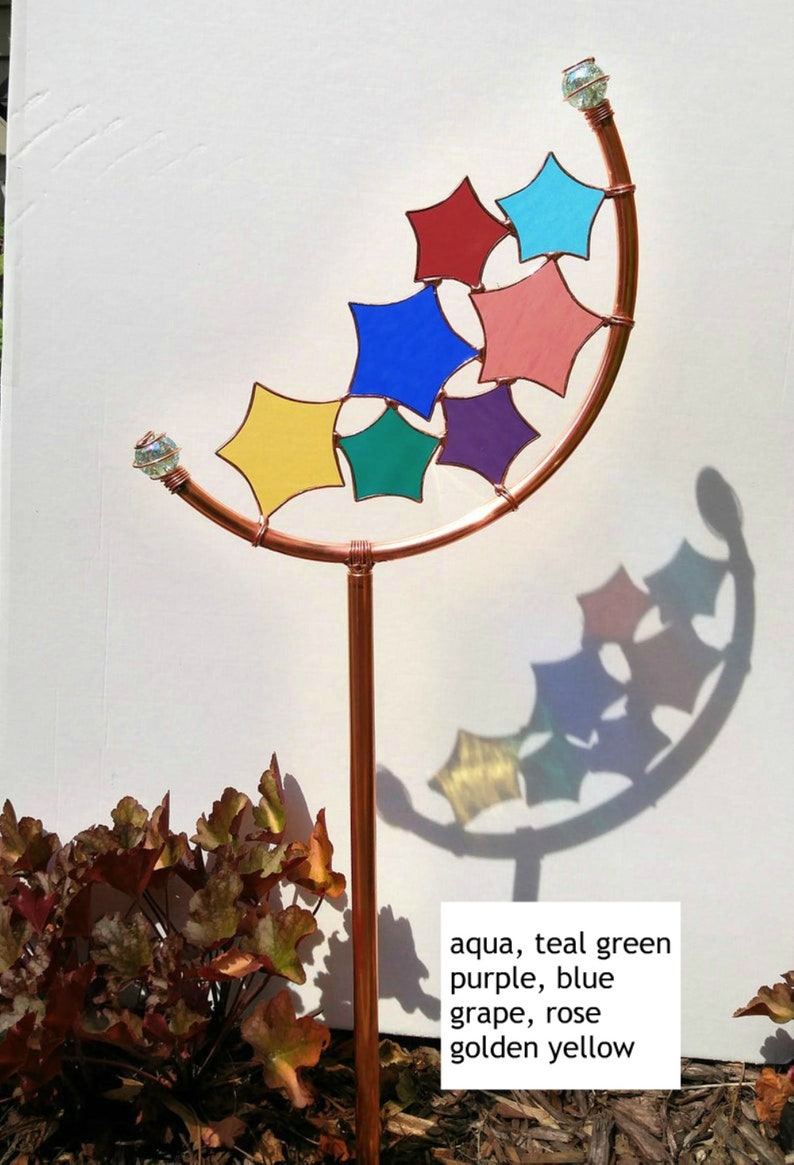 Peut inclure: Un piquet de jardin en cuivre avec un sommet incurv&eacute; et une s&eacute;rie d'&eacute;toiles en verre color&eacute;. Les &eacute;toiles sont de couleur aqua, vert sarcelle, violet, bleu, rose et jaune dor&eacute;. Le texte "aqua, teal green purple, blue grape, rose golden yellow" est &eacute;crit sous le piquet.