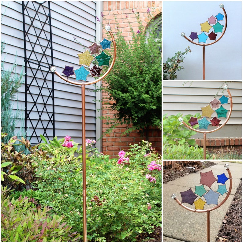 Peut inclure: Un piquet de jardin en cuivre avec un motif de croissant de lune et des &eacute;toiles en verre color&eacute; dans des tons de bleu, vert, violet et or. Le piquet est pr&eacute;sent&eacute; dans trois positions diff&eacute;rentes dans un jardin.