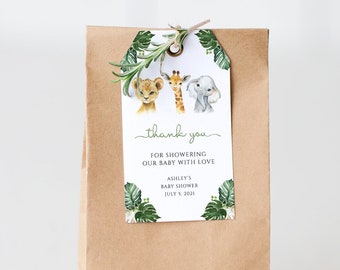 May include: A brown paper bag with a thank you tag attached. The tag features a watercolor illustration of a lion, giraffe, and elephant with green leaves. The text on the tag reads "thank you for showering our baby with love" and "Ashley's Baby Shower July 9, 2023".