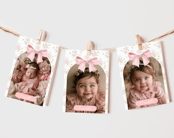 May include: A set of three floral-patterned photo cards with pink bows and a baby girl's photo in each. The cards are labeled "1 month", "6 months", and "12 months".