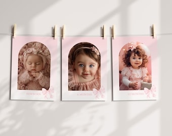 May include: Three baby milestone prints, each featuring a different photo of a baby girl. The prints are in pink arch frames with the text "NEWBORN", "6 MONTHS", and "12 MONTHS". Each print is held by a wooden clothespin.
