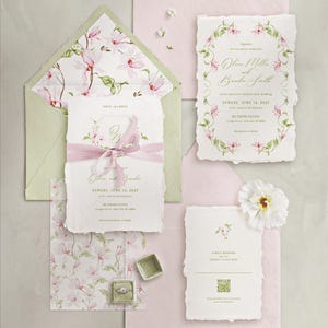 Può includere: Set di cancelleria per matrimoni con disegni floreali rosa e verdi. Include inviti, biglietti di invito e una busta con motivi floreali coordinati. È presente anche un portagioie con un anello.