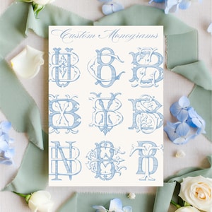 Könnte beinhalten: Eine cremefarbene Karte mit neun hellblauen, individuellen Monogrammen in verschiedenen verzierten Stilen. Die Worte "Custom Monograms" sind oben in Kursivschrift geschrieben. Das Bild ist von hellblauen Blumen und Bändern umgeben.