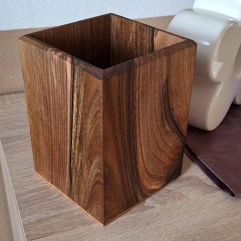 May include: A square wooden container with a rich, dark brown finish. The container has a smooth, polished surface and a natural wood grain pattern. The open top reveals the hollow interior. The container is likely used for storage or display.