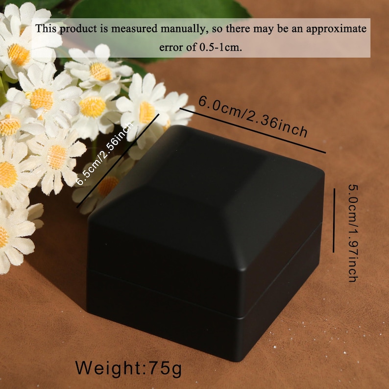 K&ouml;nnte beinhalten: Eine schwarze, geometrische Schmuckschatulle mit den Ma&szlig;en 6,0 cm x 6,5 cm und 5,0 cm. Die Box wiegt 75g. Der Text auf dem Bild besagt, dass die Produktma&szlig;e einen ungef&auml;hren Fehler von 0,5-1 cm aufweisen k&ouml;nnen.