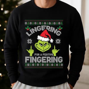 May include: Black sweatshirt featuring a Grinch design in a Santa hat, giving the middle finger. The text reads "LINGERING FOR A FESTIVE FINGERING". The design includes snowflakes and Christmas tree patterns.