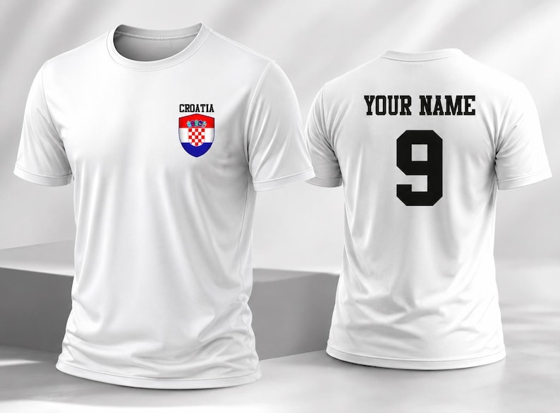 K&ouml;nnte beinhalten: Ein wei&szlig;es Kurzarm-T-Shirt mit dem kroatischen Wappen und dem Wort CROATIA auf der linken Brustseite. Die R&uuml;ckseite des T-Shirts zeigt den Text YOUR NAME in schwarzen Blockbuchstaben &uuml;ber der gro&szlig;en schwarzen Ziffer 9.