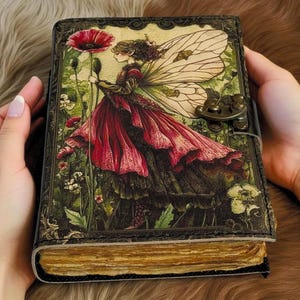 K&ouml;nnte beinhalten: Ein ledergebundenes Notizbuch mit einer Fantasy-Illustration auf dem Einband. Der Einband zeigt eine Fee in einem roten Kleid, die eine Mohnblume h&auml;lt. Das Notizbuch hat einen Metallverschluss und gealterte Seiten. Das Design hat eine Vintage- und skurrile &Auml;sthetik.