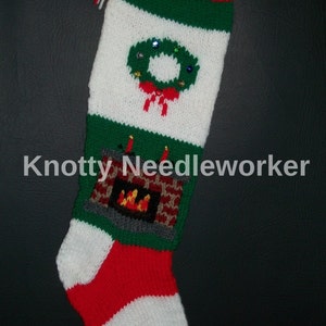 May include: A knitted Christmas stocking with a red, white, and green striped pattern. The stocking features a green wreath with red ribbon and a fireplace with a fire.