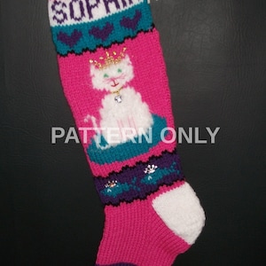 May include: Pink knitted Christmas stocking with a white cat wearing a crown and a jewel necklace. The stocking has a teal and purple stripe with white hearts and the name "Sophia" at the top.