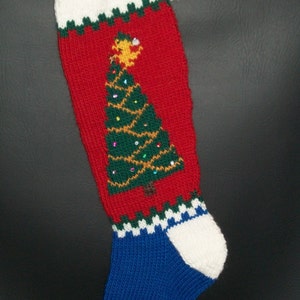 May include: A red, white, blue, and green knitted Christmas stocking with a green Christmas tree design and a bell at the top.