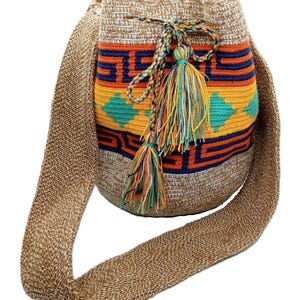 Puede incluir: Bolso de hombro de crochet beige hecho a mano con un diseño geométrico colorido en naranja, amarillo, turquesa y azul marino. El bolso tiene una correa larga tejida y borlas decorativas multicolores. Un accesorio elegante y único.