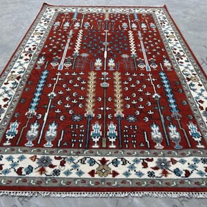 Alfombra de lana anudada a mano en rojo, marfil y azul con patrón tribal de árbol y columna, diseño geométrico simétrico, hecha a mano para sala de estar y dormitorio.
