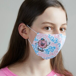 May include: A white face mask with a pink and blue donut character wearing a hat and skateboarding on a blue and pink swirl pattern.
