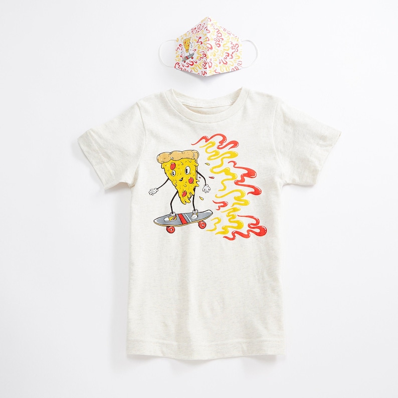 Puede incluir: Una camiseta blanca con una rebanada de pizza de dibujos animados en una patineta. La rebanada de pizza lleva un sombrero rojo y amarillo y tiene una llama roja y amarilla detr&aacute;s. El texto en la camiseta dice "Pizza Power".