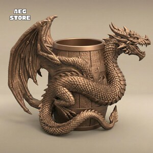 May include: Bronze-colored dragon-themed mug. The dragon wraps around a barrel-shaped mug, with its wings extended. The mug has the text "AEG STORE" in the upper left corner. The dragon has detailed scales and a menacing expression.