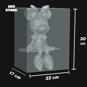 May include: A gray Minnie Mouse figure, 30 cm tall, inside a clear rectangular display case. The case measures 22 cm wide and 17 cm deep. The figure is wearing a dress with polka dots and a large bow. The text "AEG STORE" is in the upper left corner.
