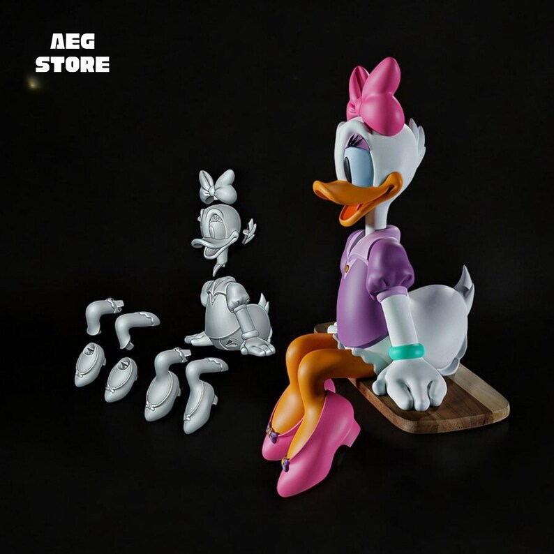 May include: A Daisy Duck figurine with a pink bow, purple top, and pink shoes. The figure is sitting on a wooden base. Additional disassembled parts are displayed nearby. The text "AEG STORE" is in the upper left corner.