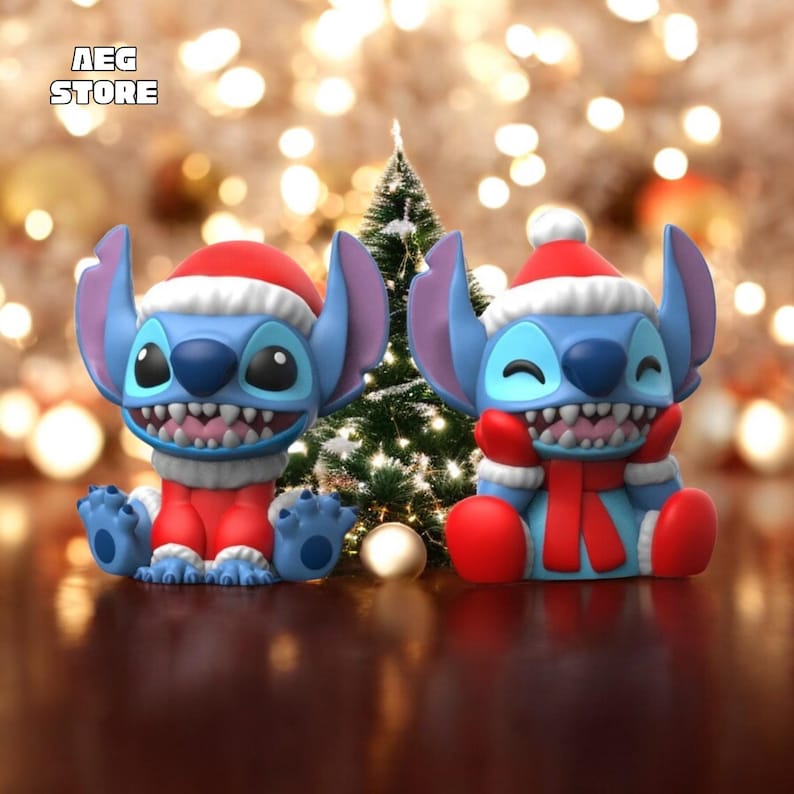 May include: Two blue cartoon character figurines, each wearing a red Santa hat and outfit, with a white trim. One figurine is smiling, and the other is winking. A small Christmas tree is in the background. The text "AEG STORE" is in the top left corner.